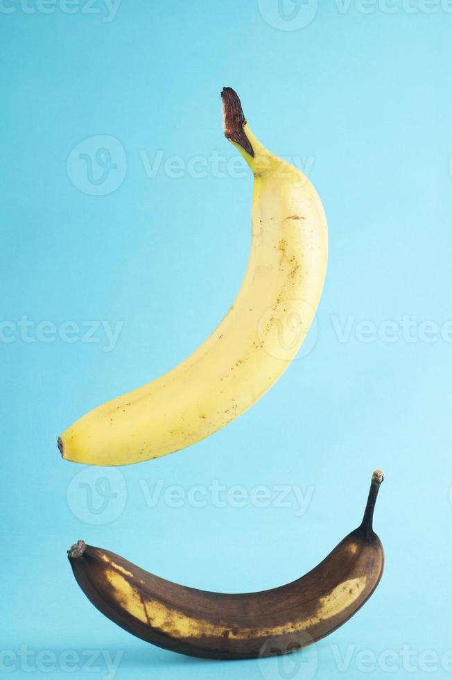verse en rotte bananen op blauwe achtergrond. echte foto van een verse banaan zwevende ob blauwe achtergrond.
