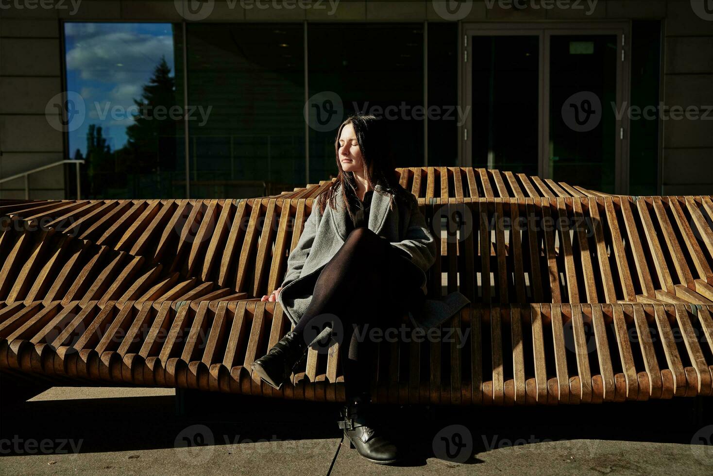 vrouw zittend Aan stad bank en genieten van zonnig zomer dag foto