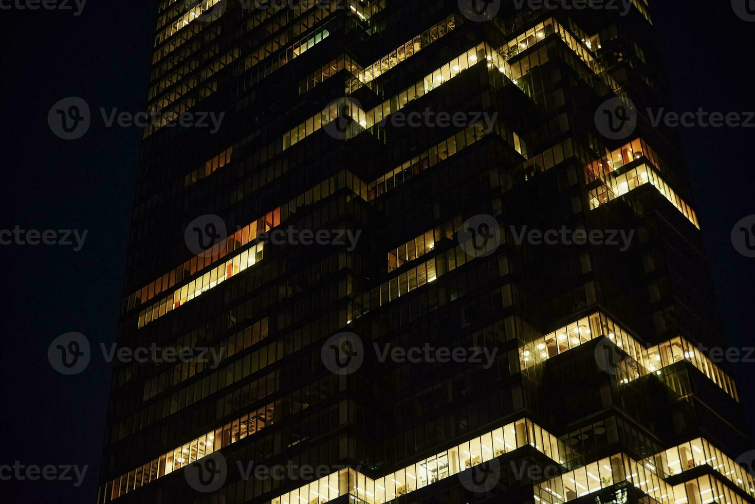 hoog stijgen kantoor gebouw met verlichte ramen Bij nacht foto