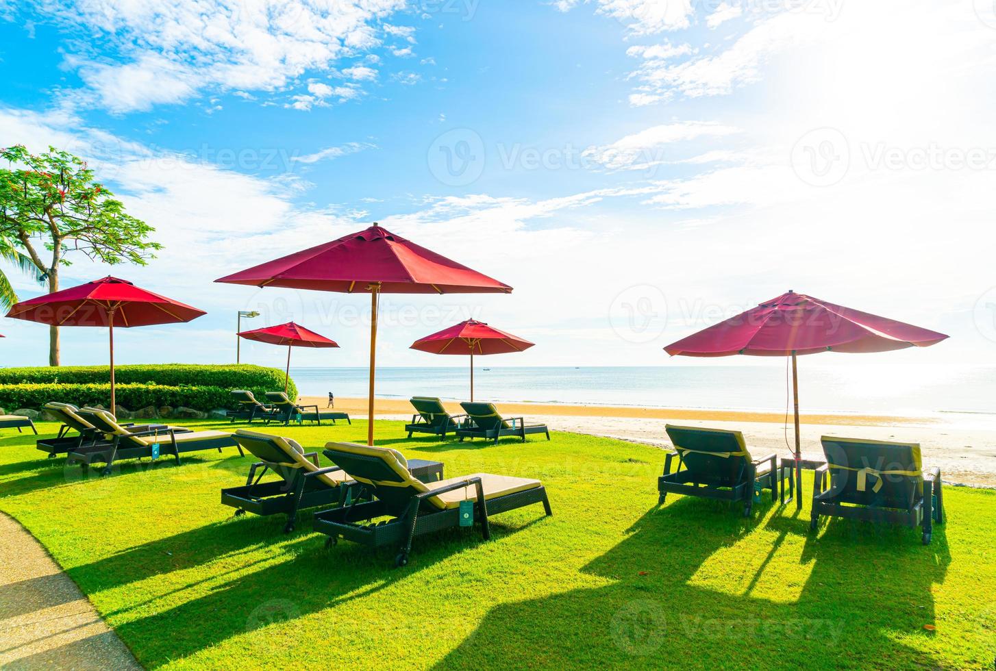 rode parasols en strandstoelen met zee strand achtergrond en blauwe lucht en zonlicht foto