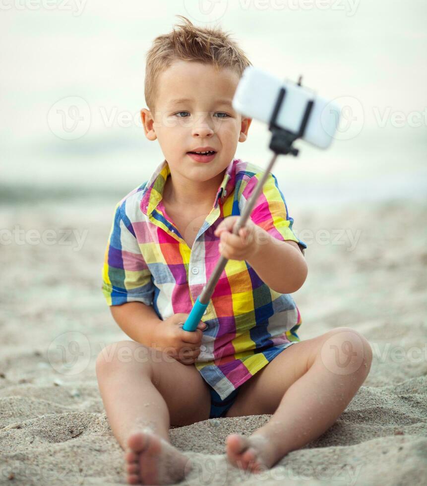 kind met telefoon en selfie stok Aan de strand foto