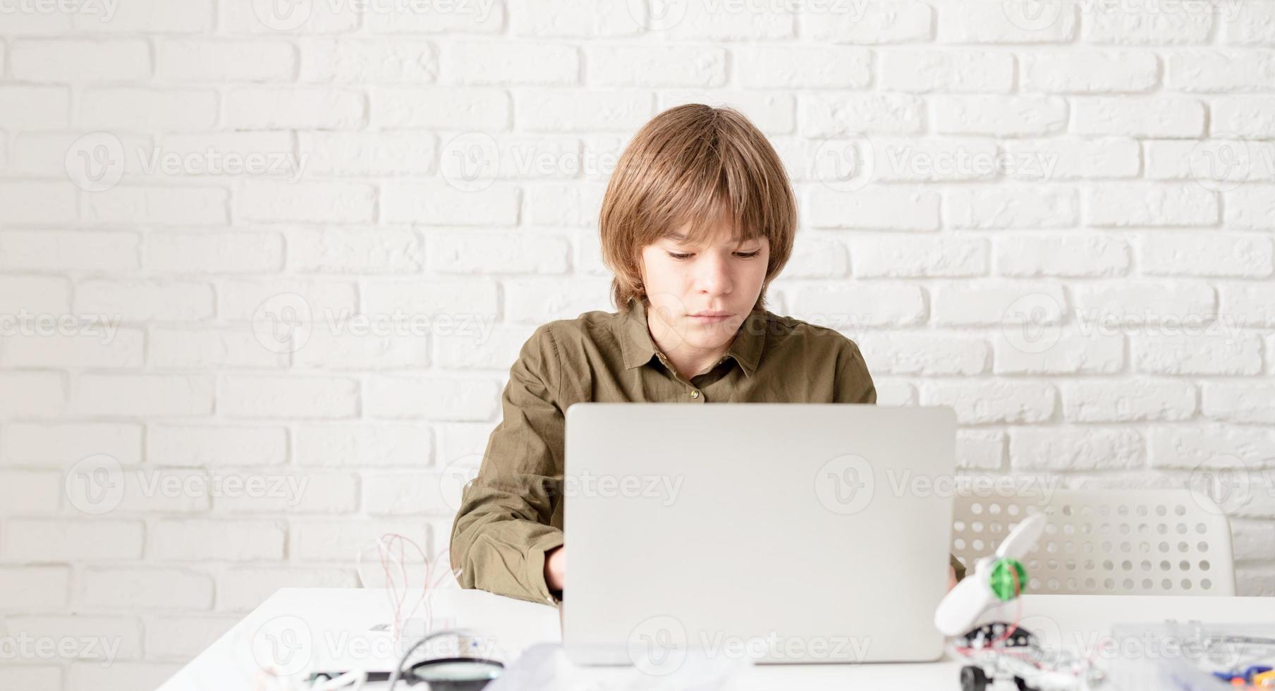 jonge jongen die thuis op de laptop werkt of studeert foto