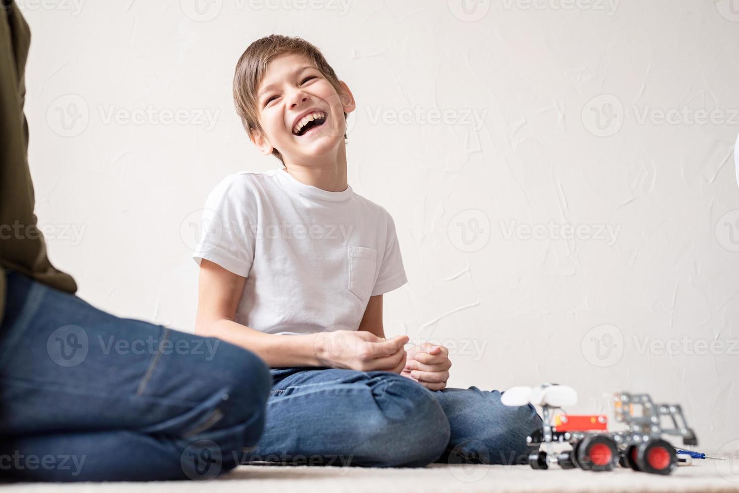 jonge jongens die plezier hebben met het bouwen van robotauto's in de werkplaats foto