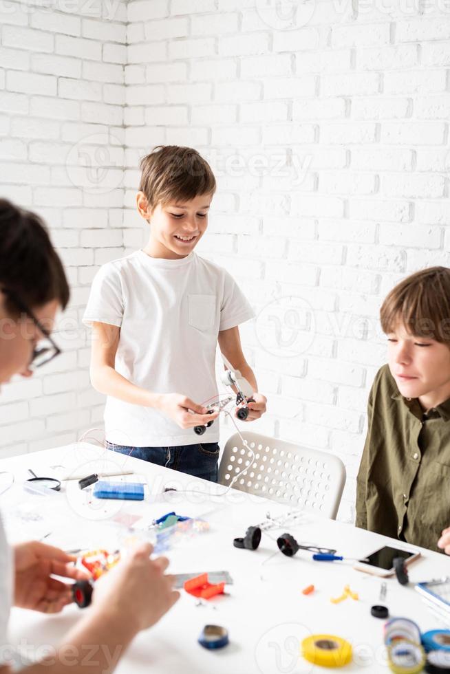 jonge jongens die plezier hebben met het bouwen van robotauto's in de werkplaats foto