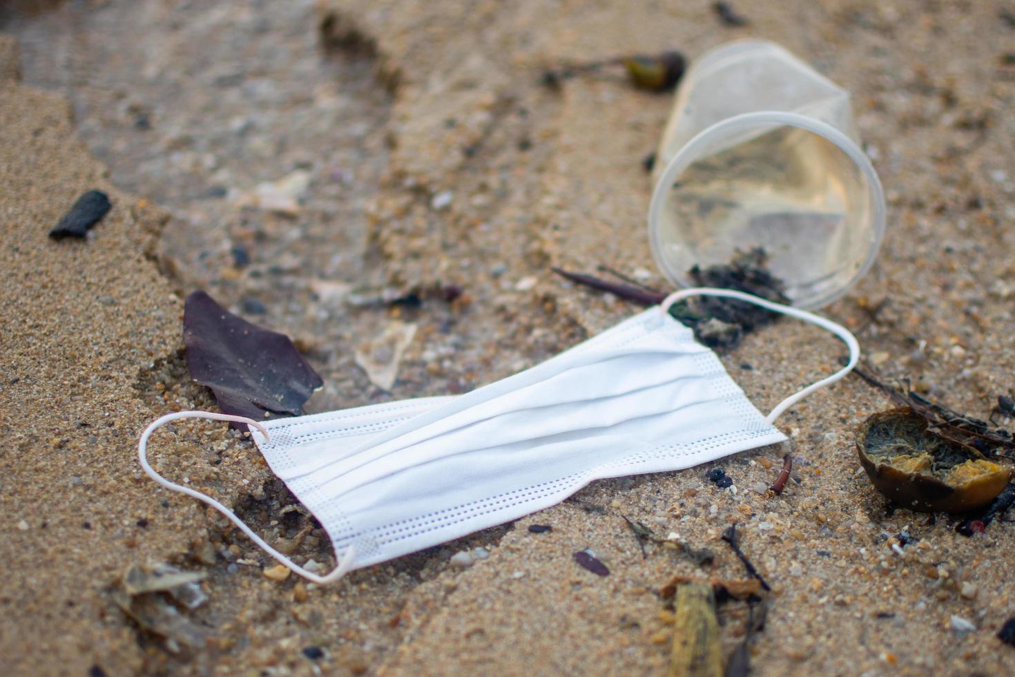 gebruikt masker tijdens covid 19 op het zandstrand werd gegooid. onderwerp is bekrast. foto