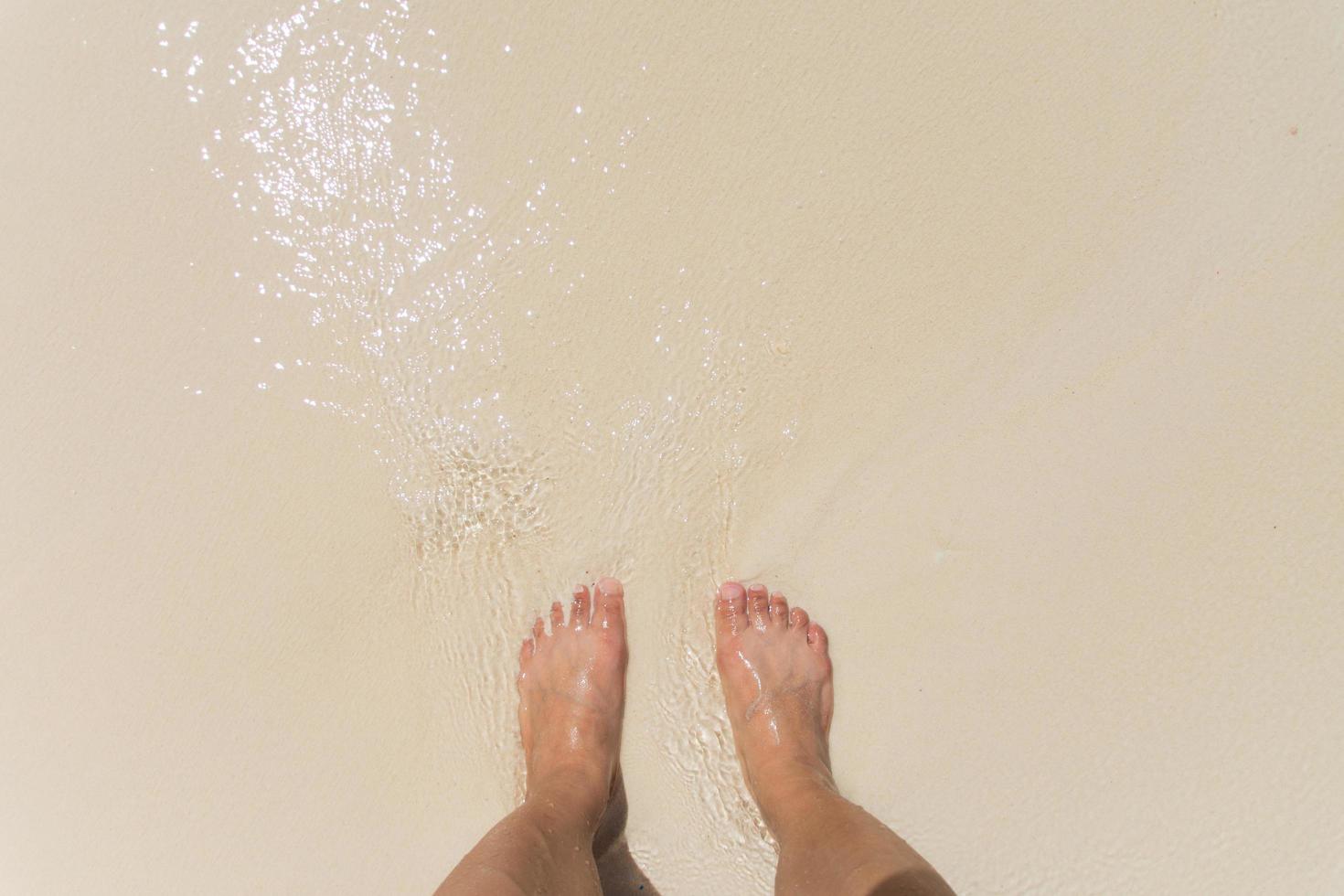 op blote voeten in de golven op het strand staan foto