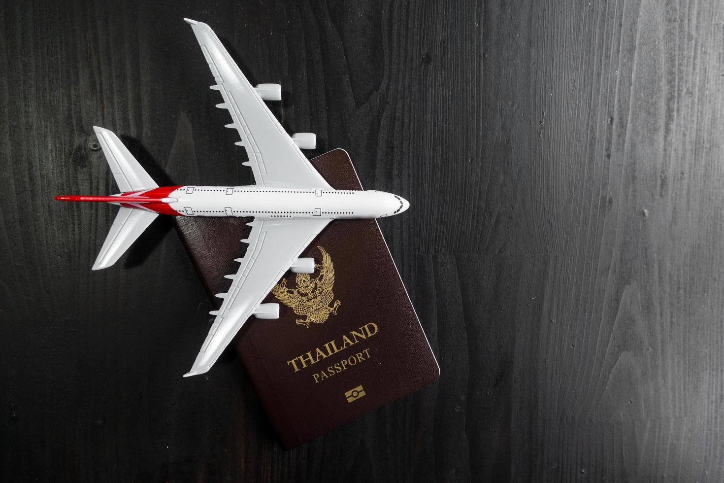 vliegtuigmodel en paspoort op houten bureau, klaar reisconcept foto