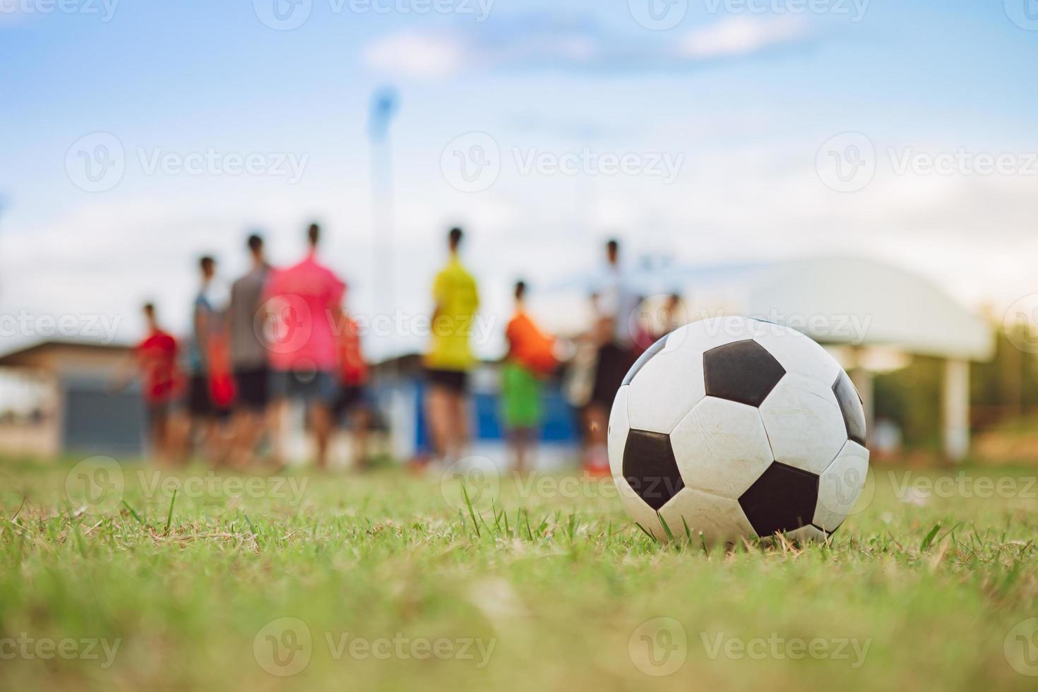 actiesport buitenshuis van een groep kinderen die plezier hebben met voetballen om te oefenen in het landelijke gebied van de gemeenschap onder de schemeringzonsondergang. foto