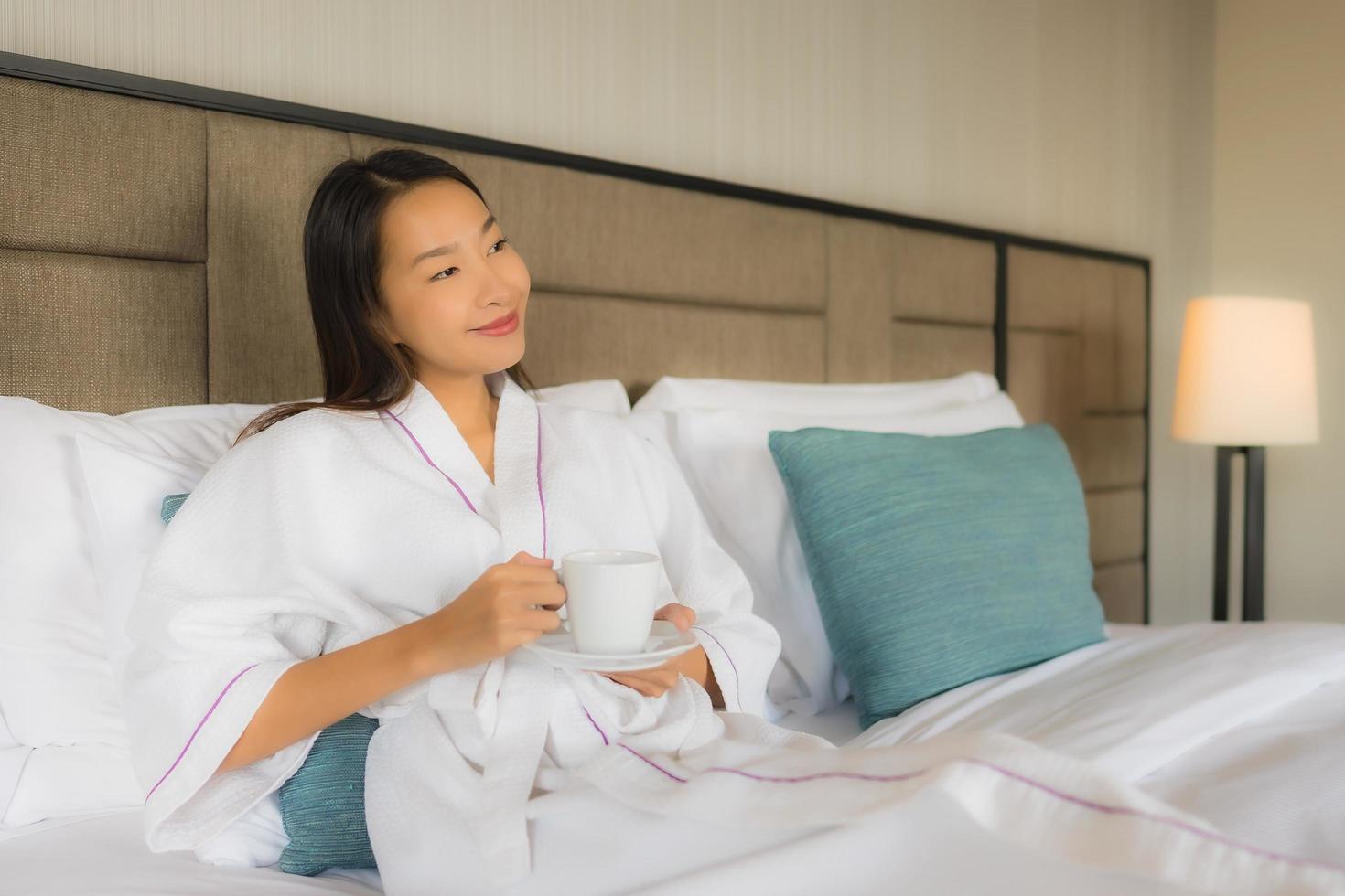 portret mooie jonge Aziatische vrouwen met koffiekopje op bed on foto