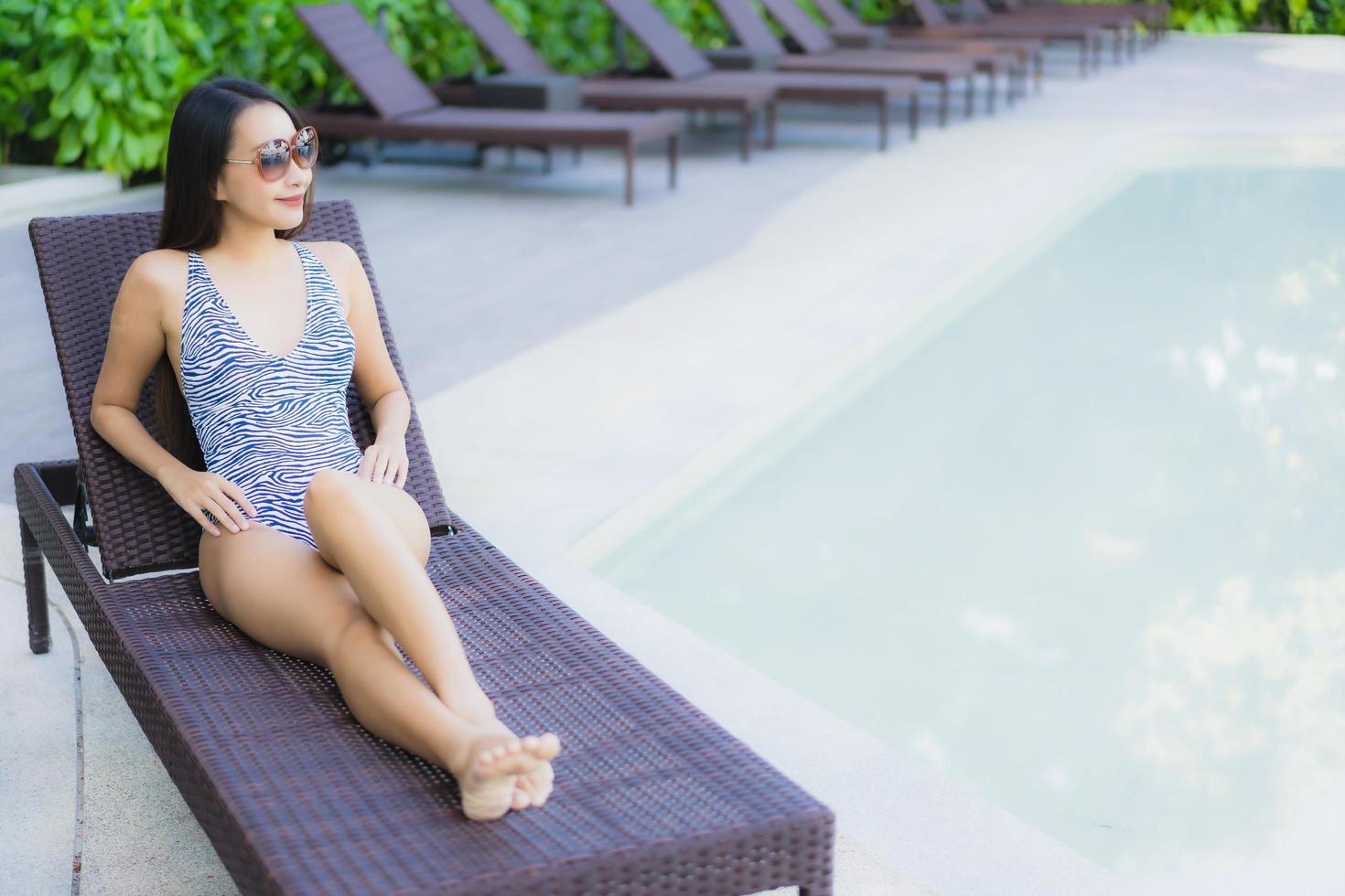 mooie jonge aziatische vrouwen gelukkige glimlach ontspannen rond het buitenzwembad in het hotelresort voor reizen in vakantievakantie foto