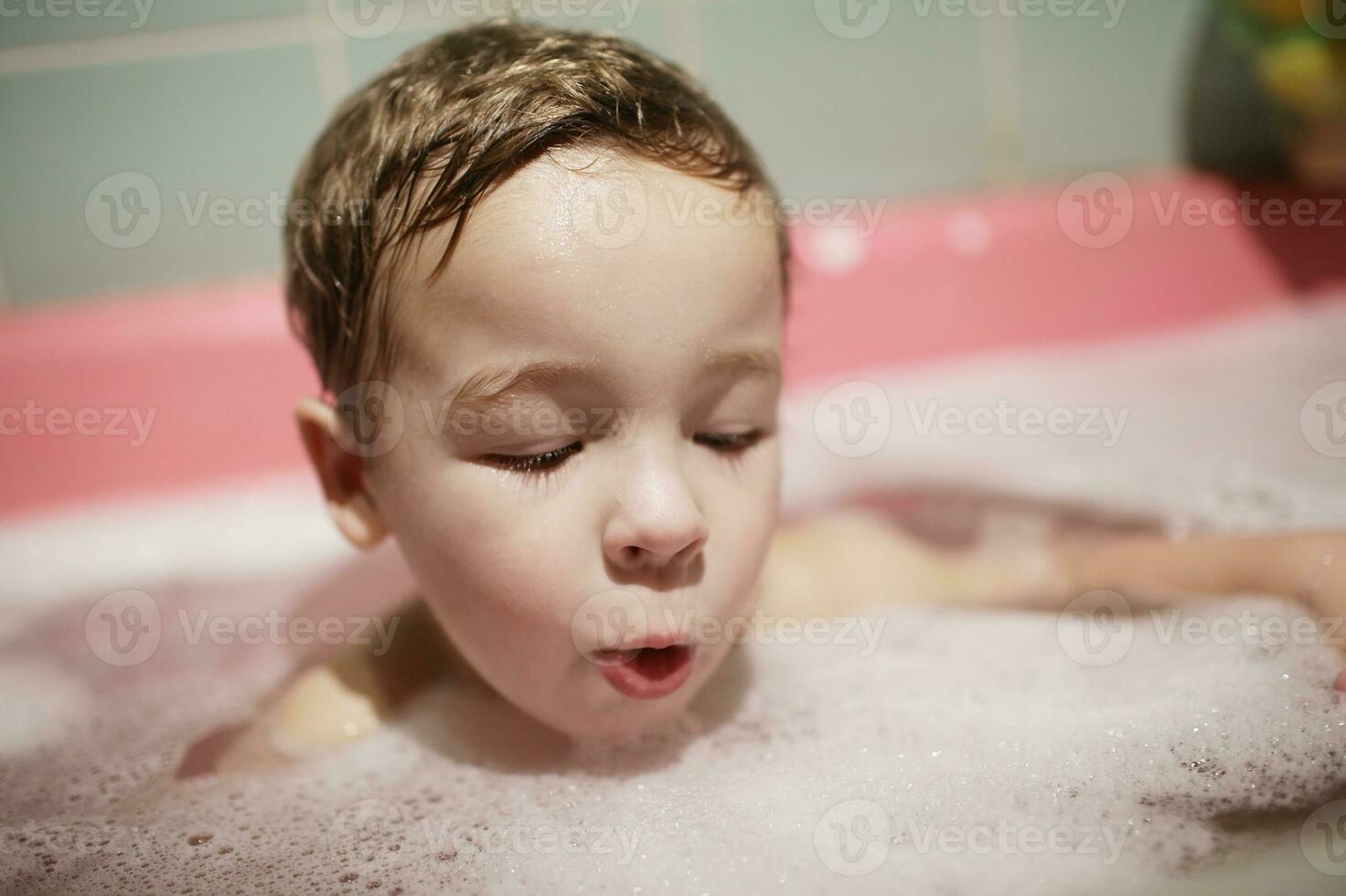 weinig jongen genieten van een schuimend bubbel bad foto