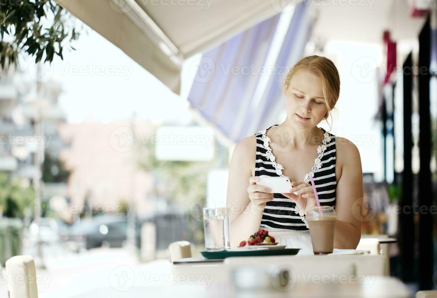 aantrekkelijk vrouw nemen afbeelding van een gebakje Aan haar mobiel foto