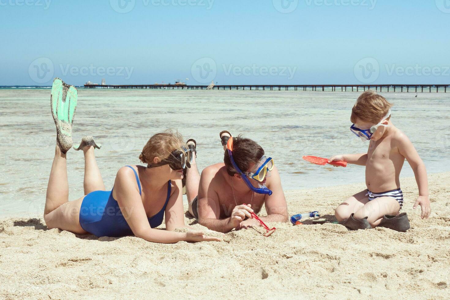 ouders en kind in snorkels spelen op het strand foto