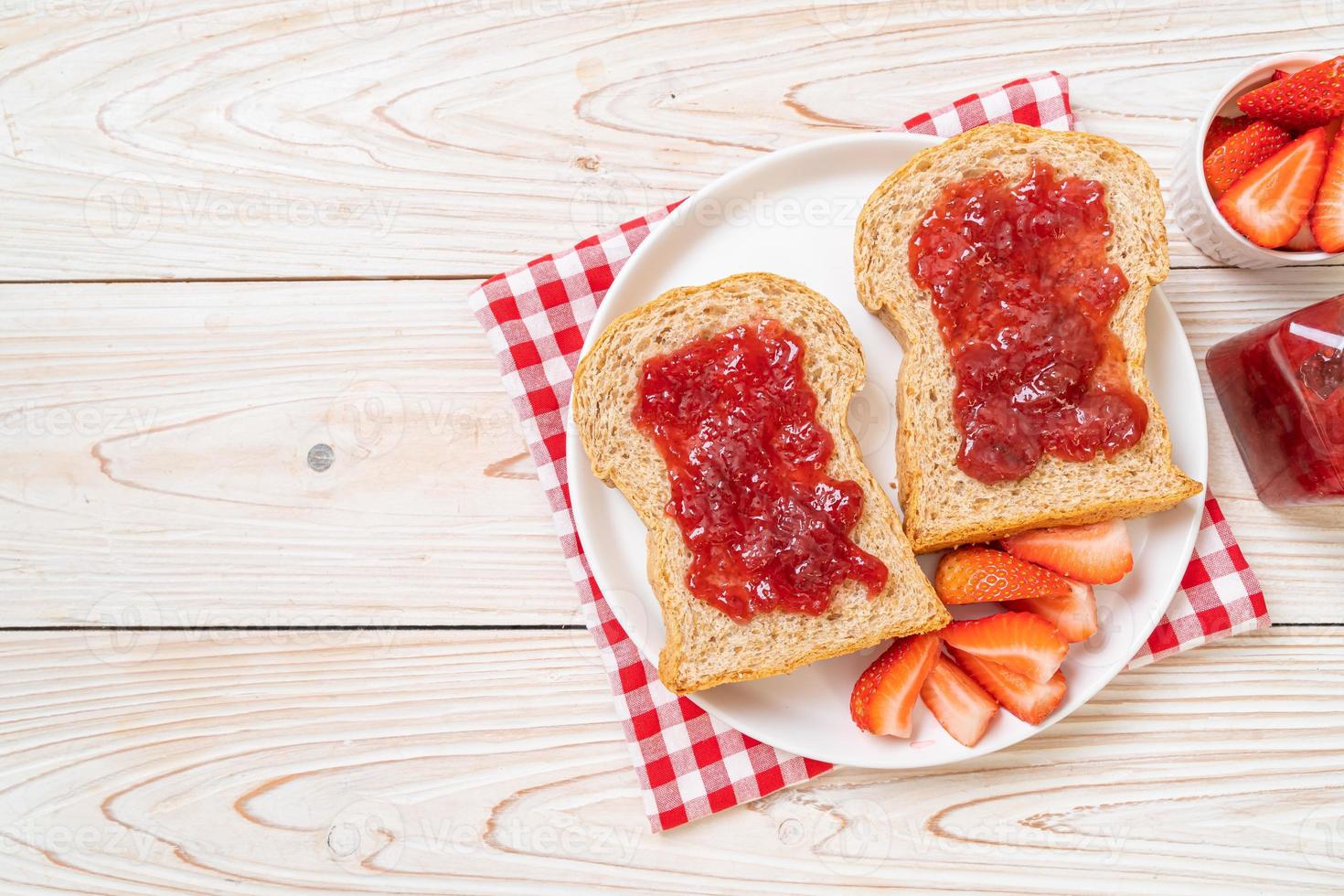 huisgemaakt volkorenbrood met aardbeienjam en verse aardbeien foto