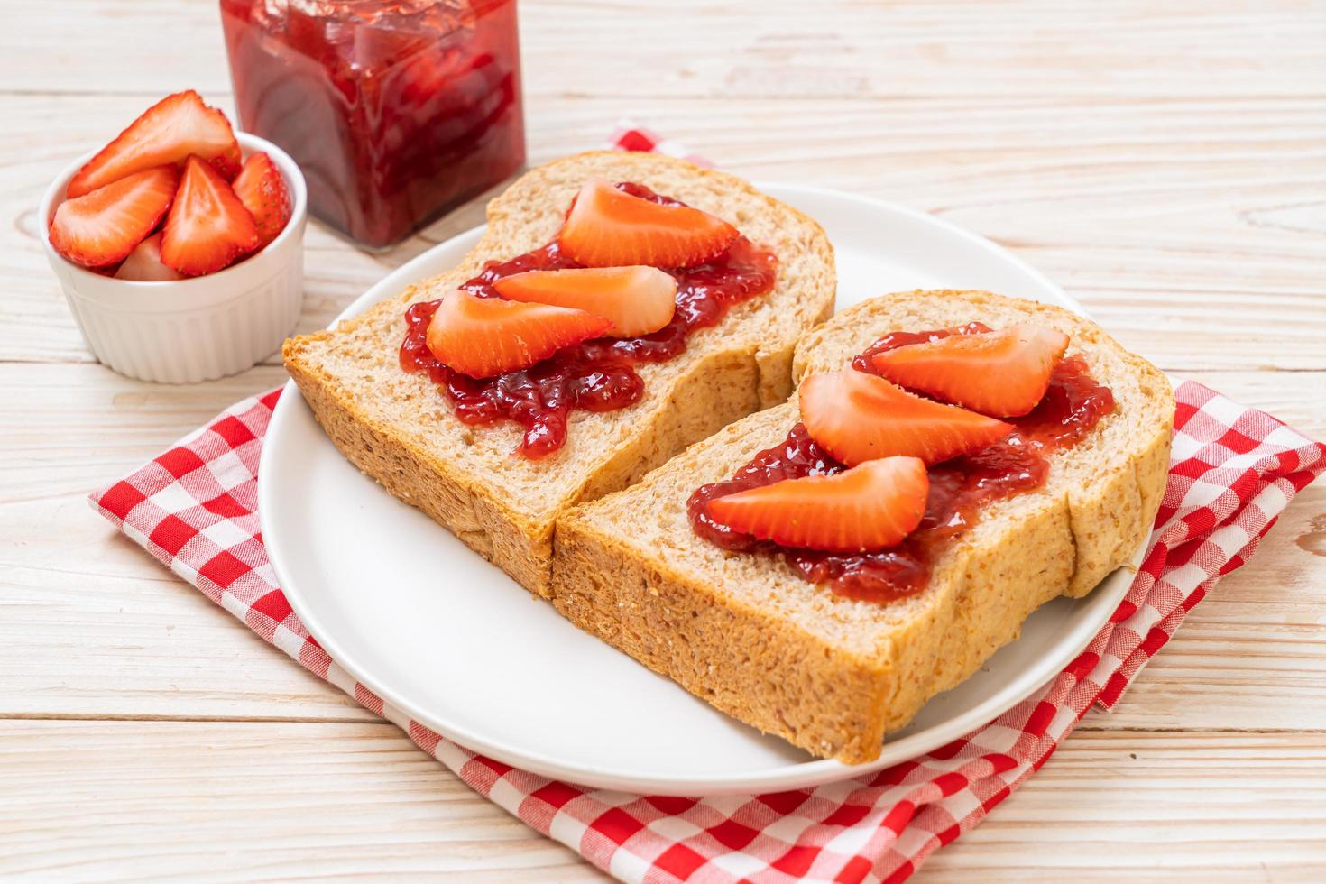 huisgemaakt volkorenbrood met aardbeienjam en verse aardbeien foto