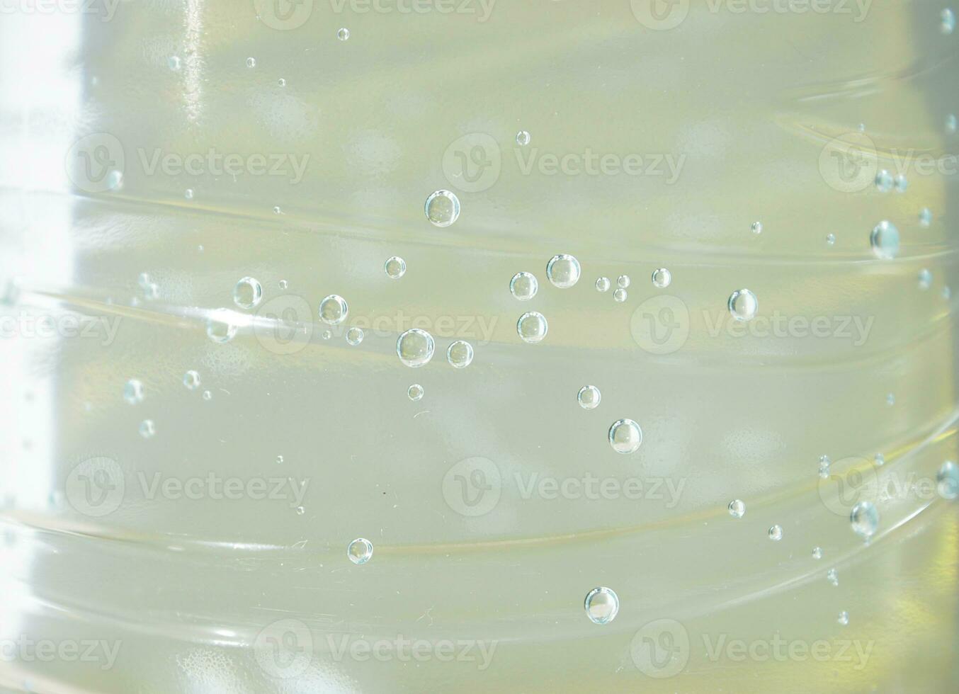 water met macro bubbels van gas. nat abstract kleur achtergrond met vloeistof transparant drinken in plastic fles. vers en verkoudheid laten vallen foto backdrop voor poster, banier, ansichtkaart, folder.