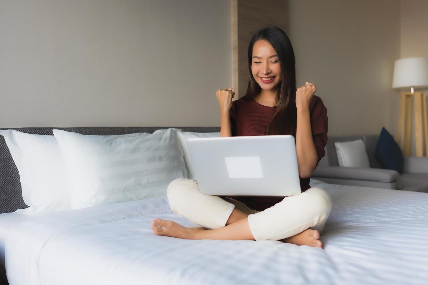 portret mooie jonge Aziatische vrouwen met behulp van computer en mobiele telefoon op bed foto