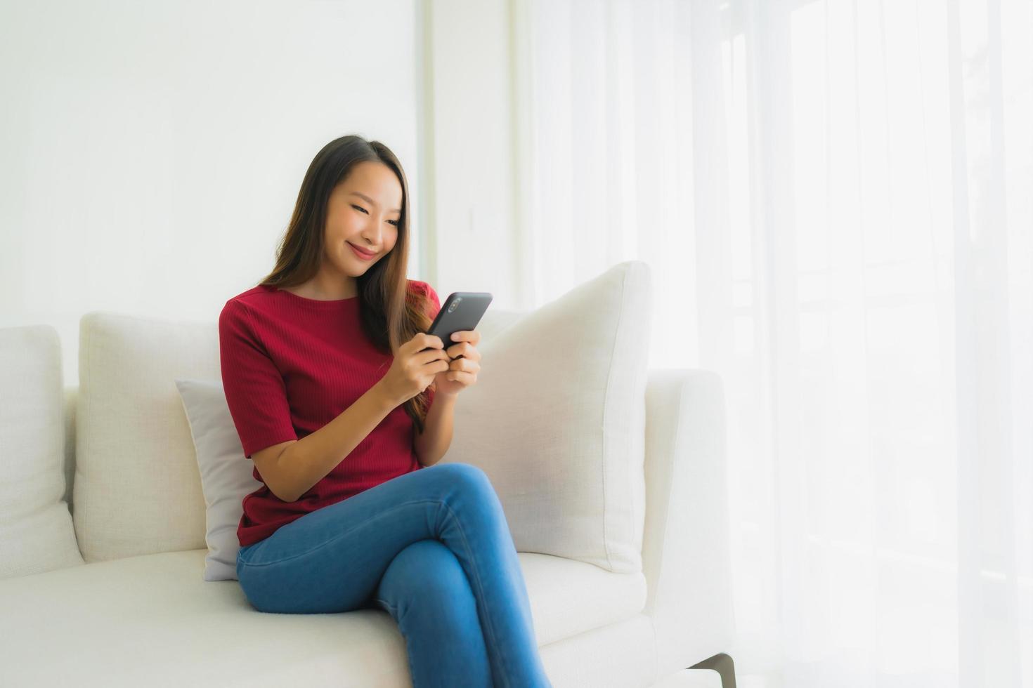 portret mooie jonge Aziatische vrouwen met behulp van mobiele of slimme telefoon op de bank foto