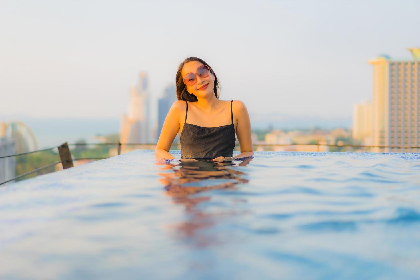 portret mooie jonge aziatische vrouwen gelukkig glimlach ontspannen buitenzwembad in hotel foto