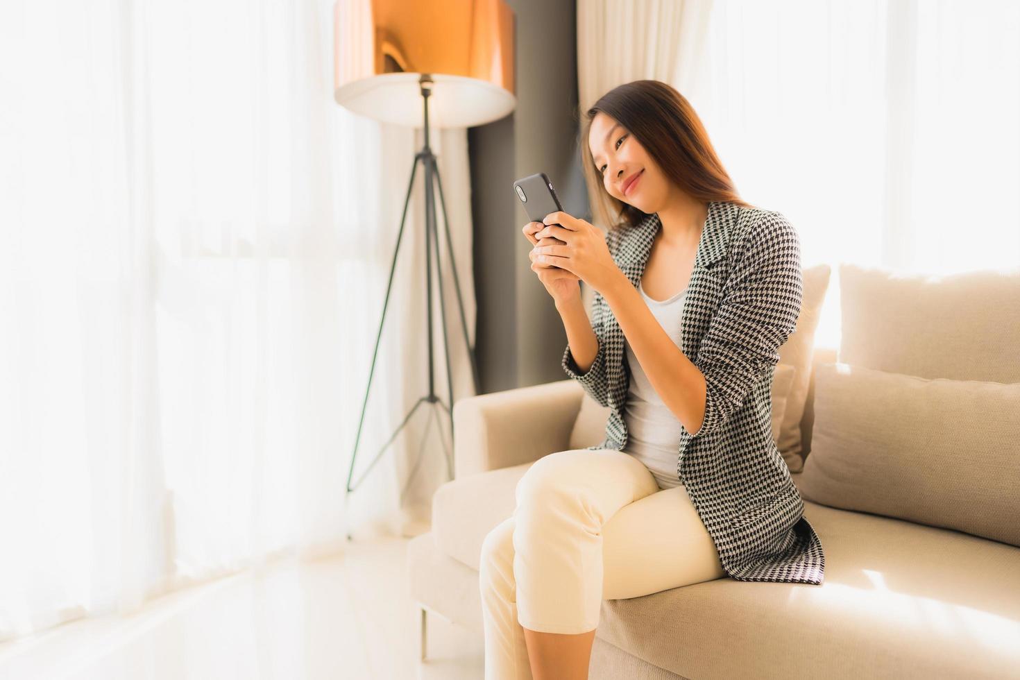 portret mooie jonge aziatische vrouwen die pratende mobiele telefoon gebruiken en op een fauteuil zitten foto