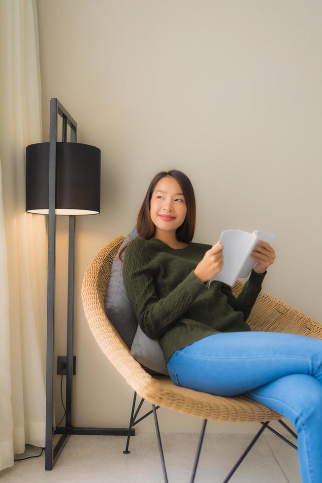 portret mooie jonge aziatische vrouwen die een boek lezen en op een fauteuil zitten foto