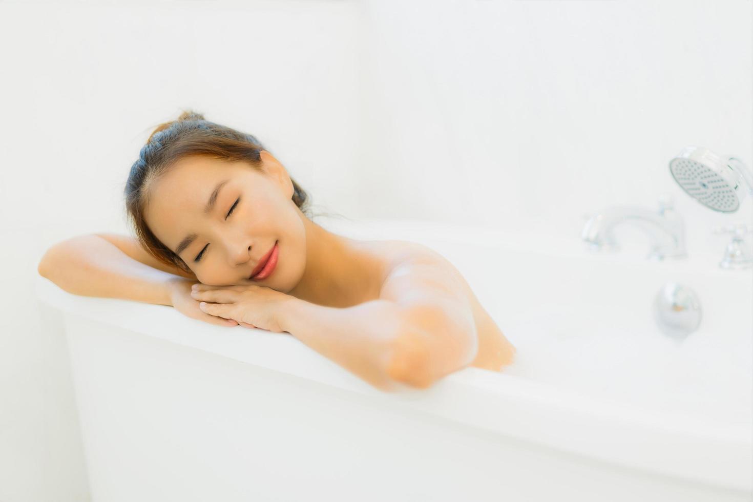 portret mooie jonge aziatische vrouw neemt een badkuip in de badkamer foto