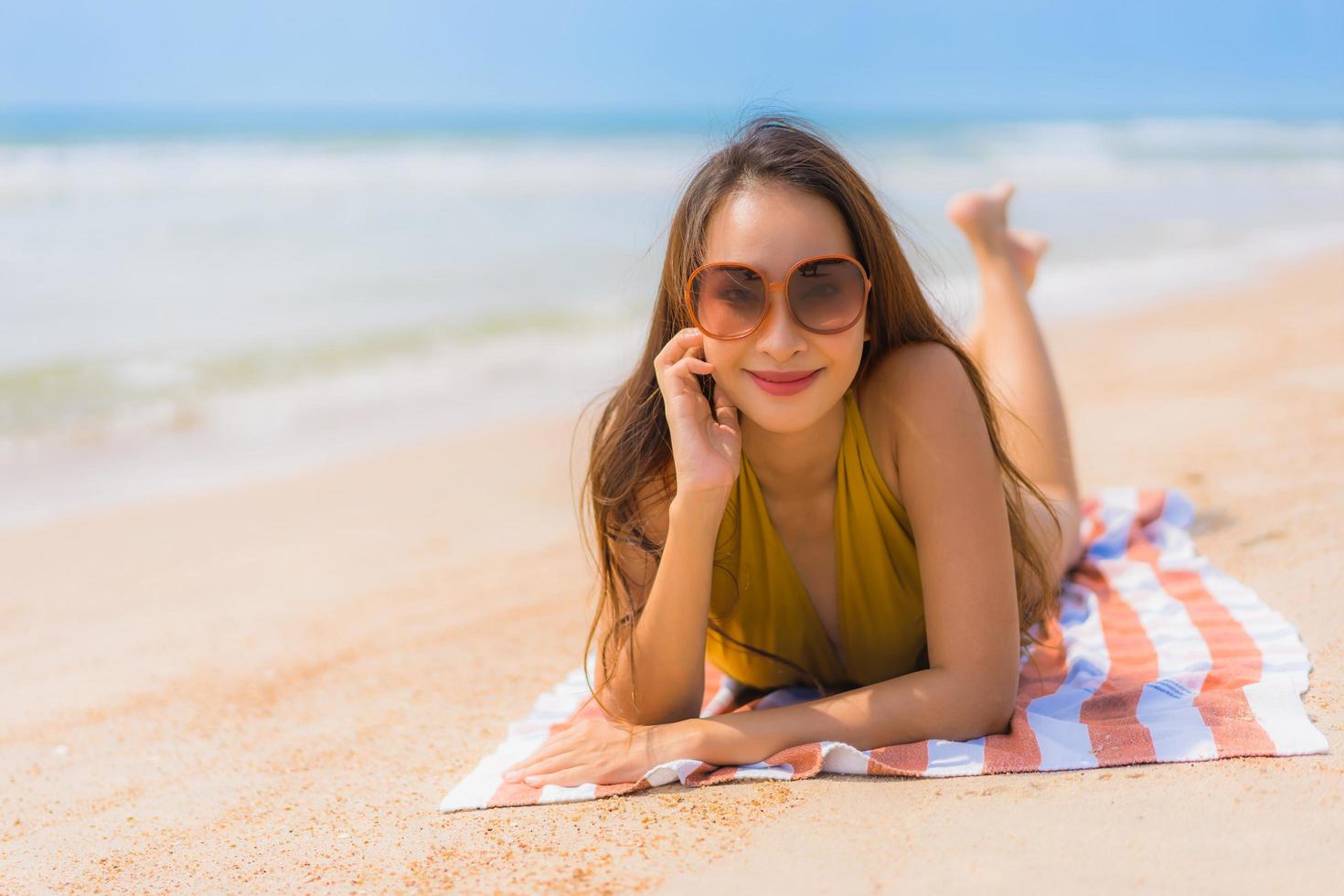 portret mooie jonge aziatische vrouw glimlach gelukkig op het strand en de zee foto