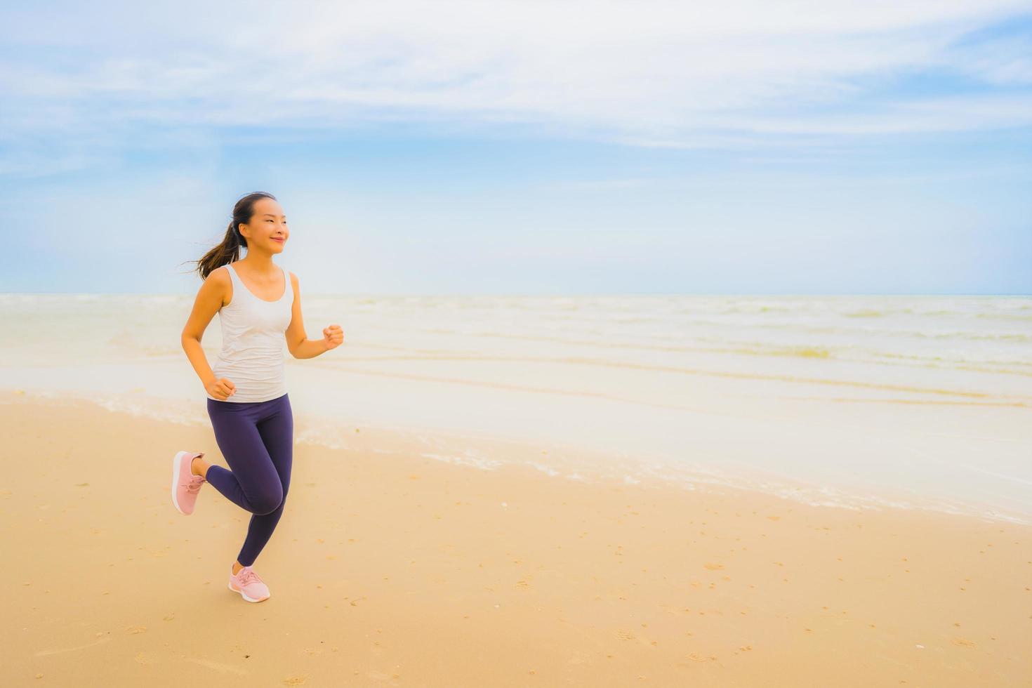portret mooie jonge sport aziatische vrouw oefenen door te rennen en joggen op het natuurstrand en de zee in de buitenlucht foto