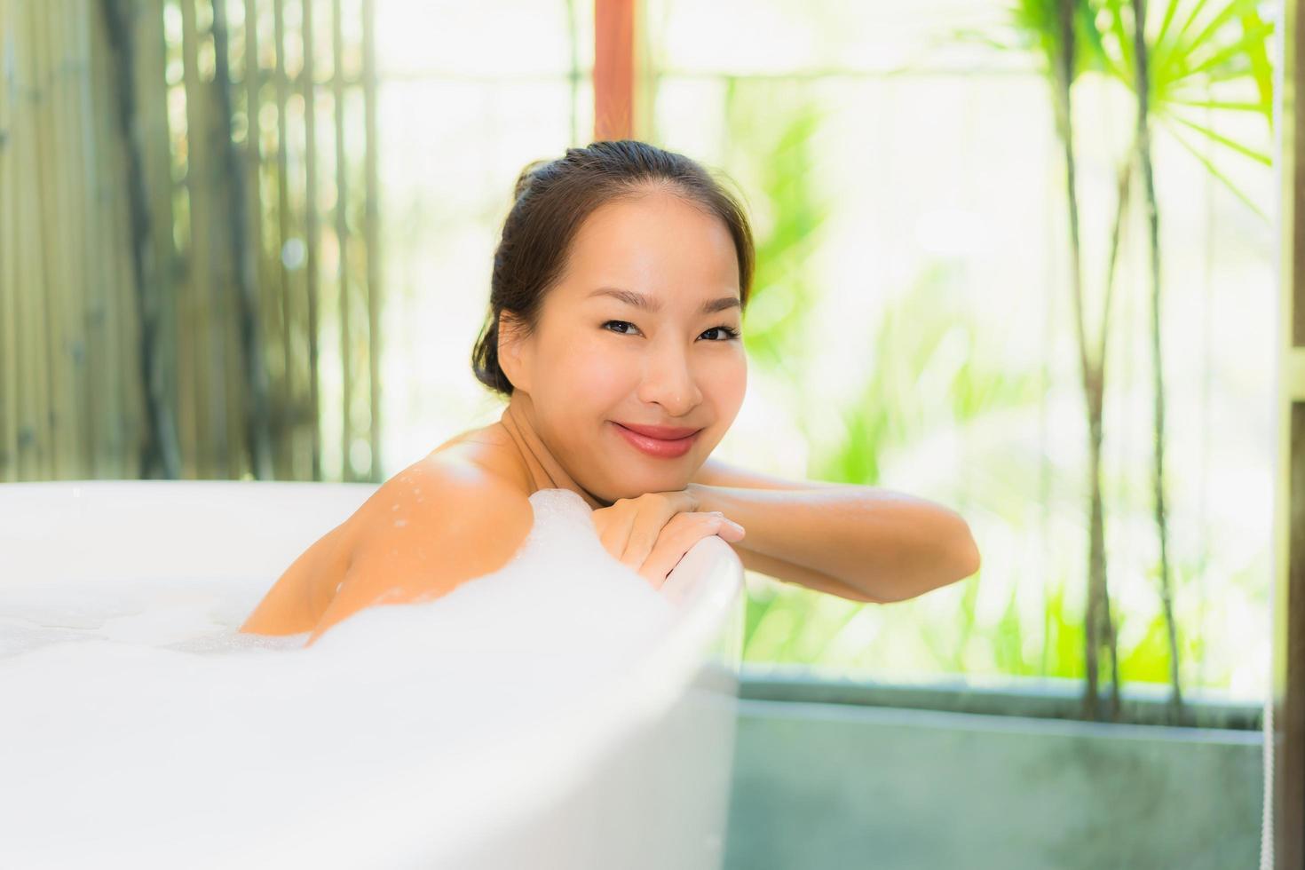 portret jonge mooie aziatische vrouw neemt een bad in badkuip foto