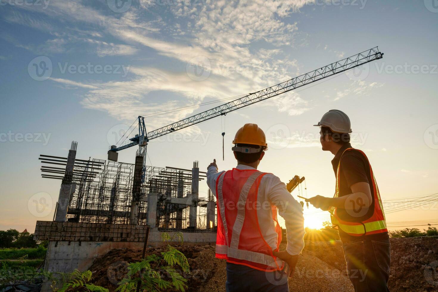 Aziatisch twee bouw ingenieurs toezien op vooruitgang van bouw project en kraan achtergrond. foto