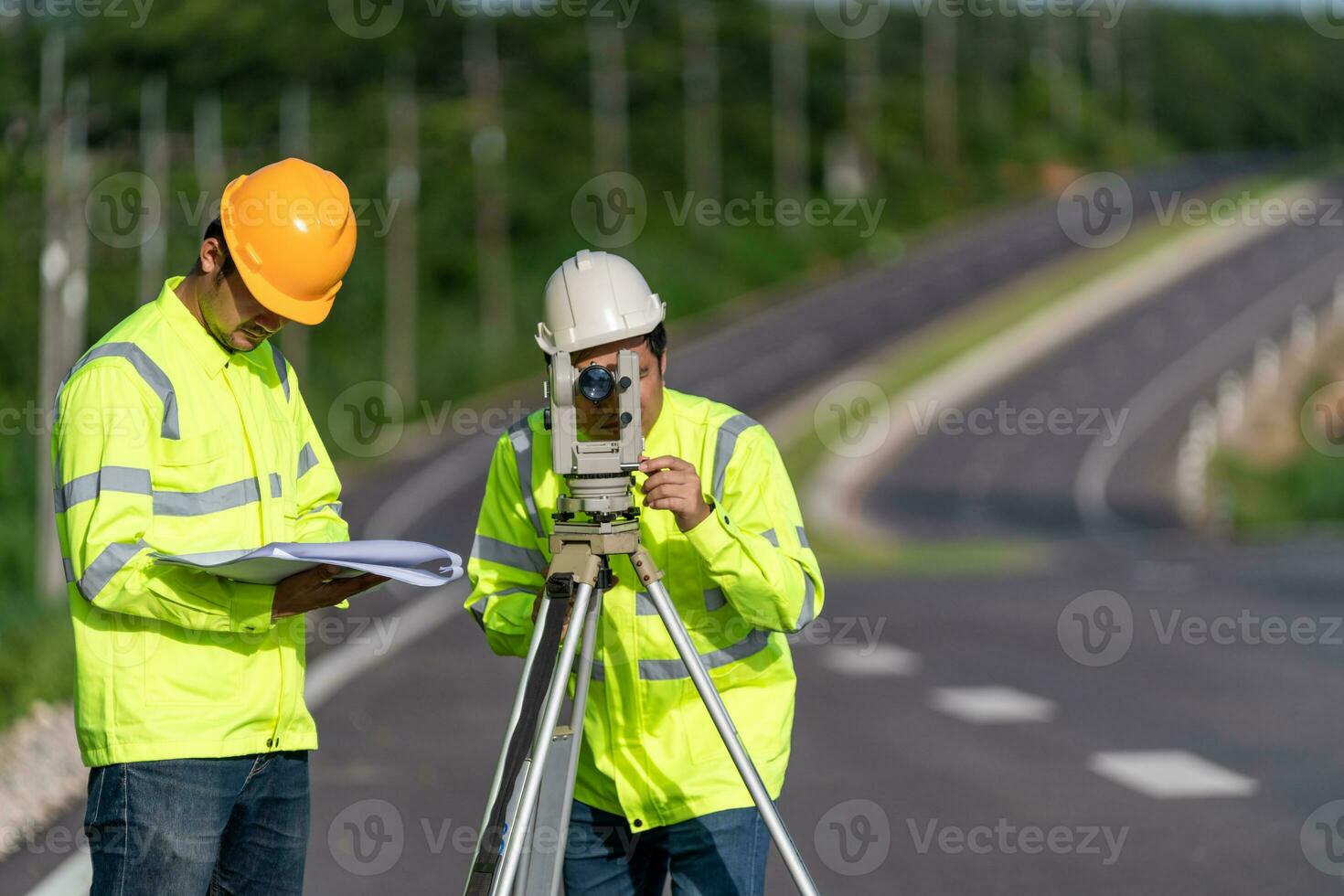 twee landmeter ingenieurs met uitrusting Aan weg bouw plaats, civiel ingenieurs, landmeter apparatuur. foto