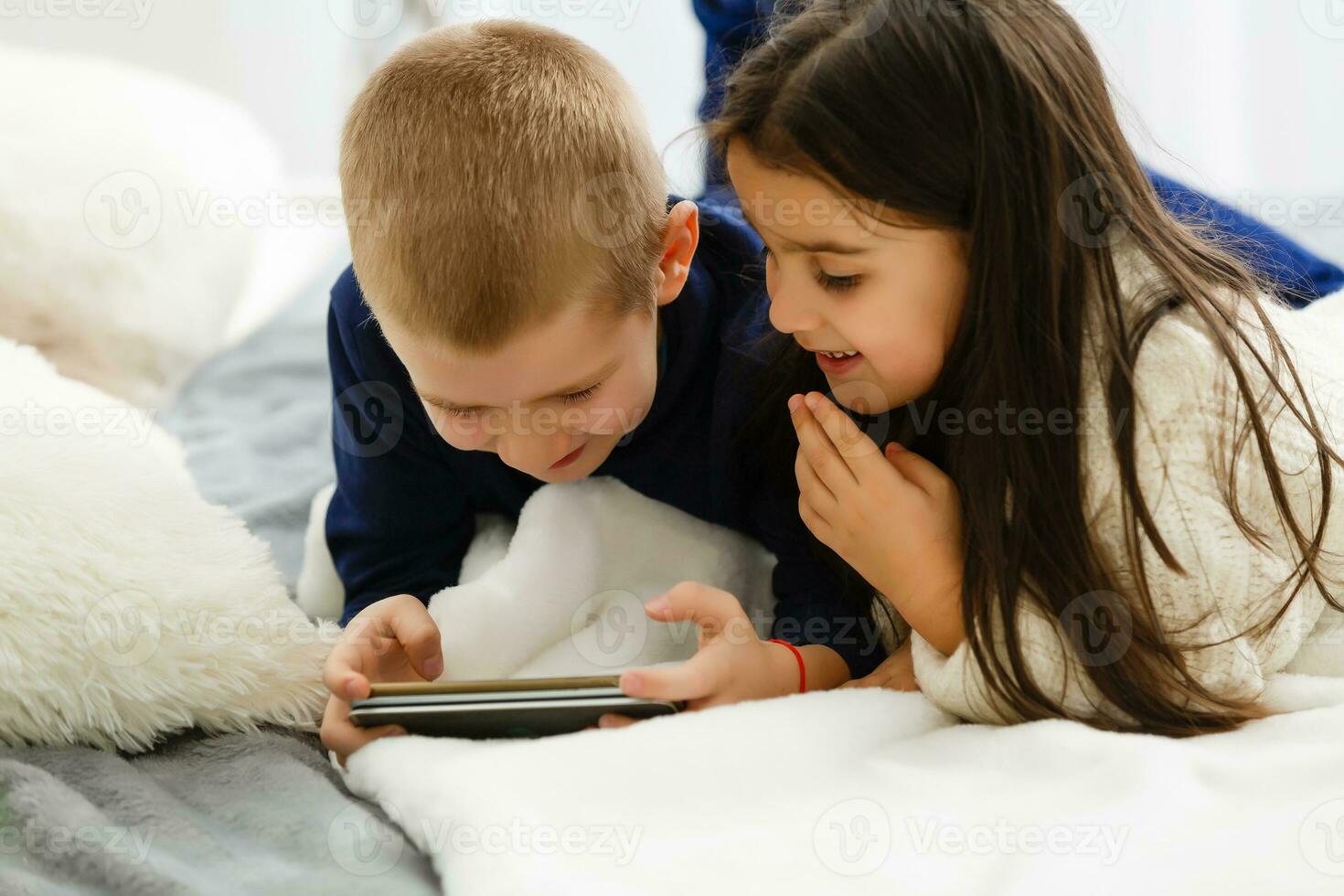 mensen, kinderen, technologie, vrienden en vriendschap concept - gelukkig weinig meisjes jongen met smartphones aan het liegen Aan verdieping Bij huis foto