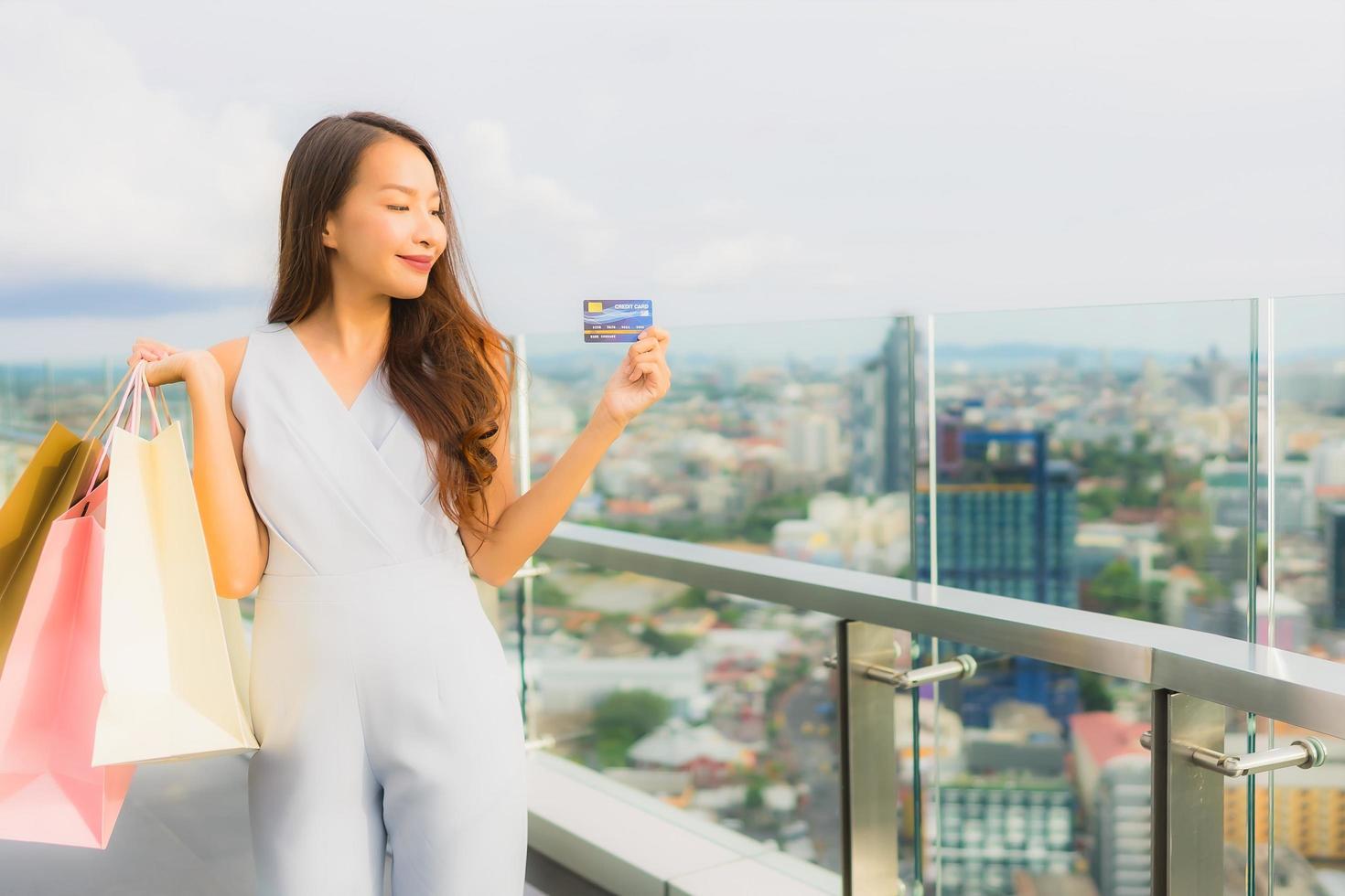 portret mooie jonge aziatische vrouw blij en glimlach met creditcard voor boodschappentas van warenhuis foto