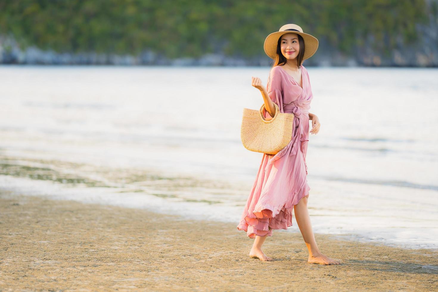 portret jonge mooie Aziatische vrouw lopen glimlach en gelukkig op het strand zee en oceaan and foto