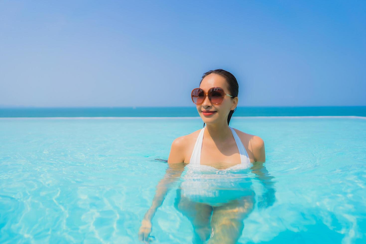 portret mooie jonge aziatische vrouw gelukkige glimlach ontspannen in het zwembad voor reisvakantie foto