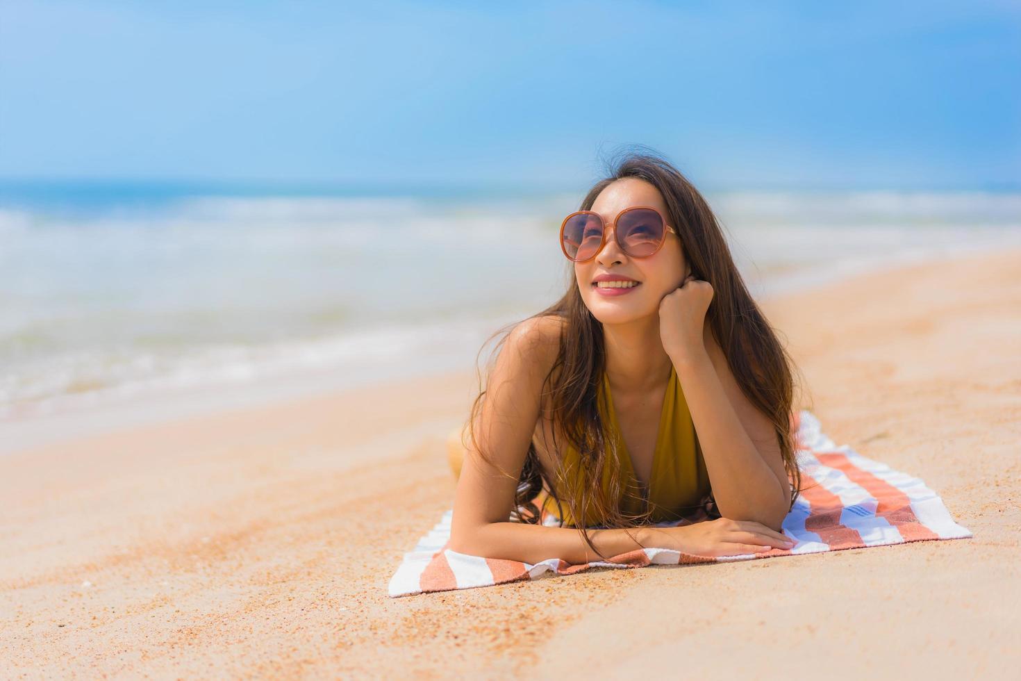 portret mooie jonge aziatische vrouw glimlach gelukkig op het strand en de zee foto