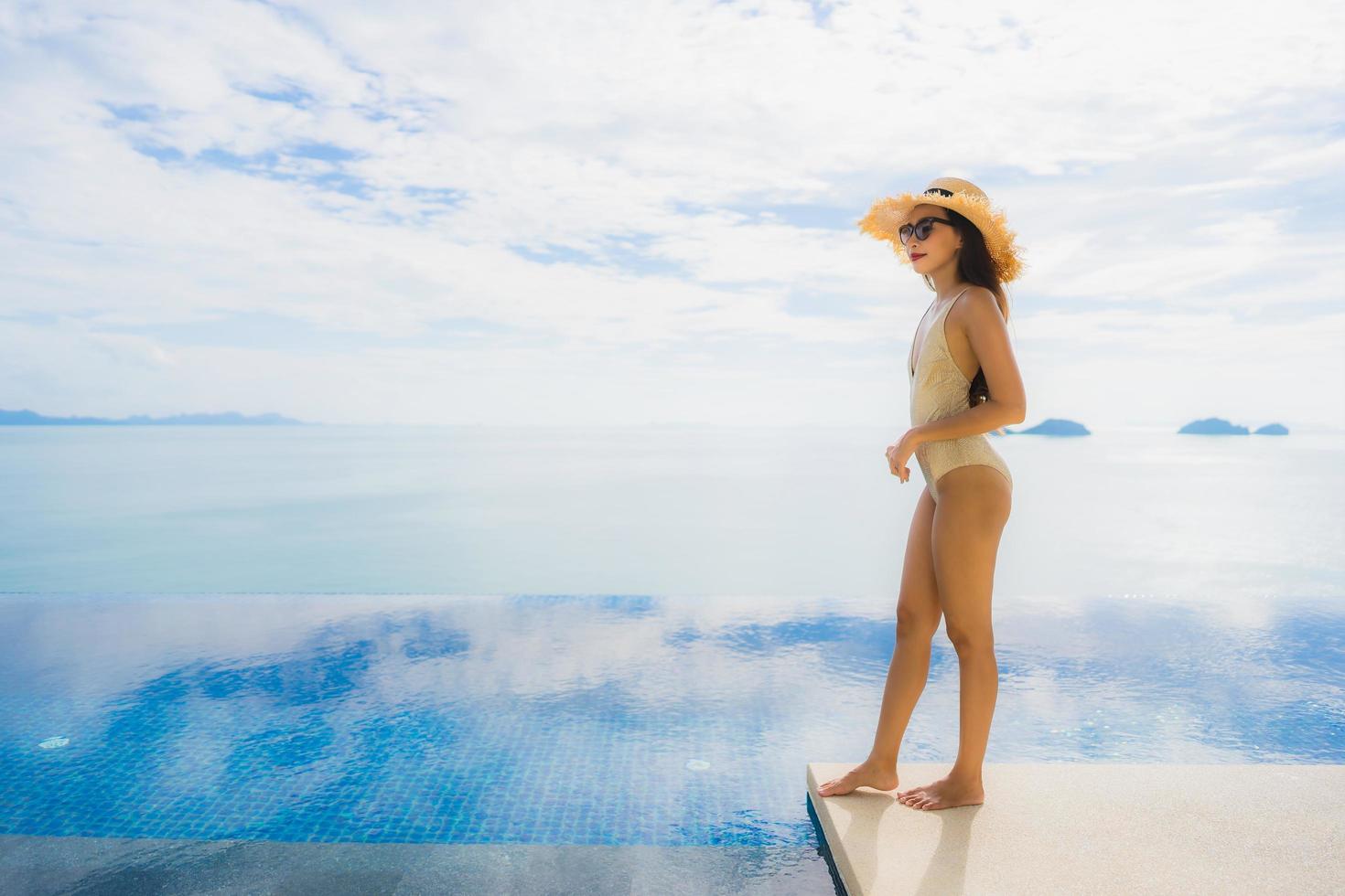 portret jonge aziatische vrouw ontspannen glimlach gelukkig rond het zwembad in hotel en resort foto