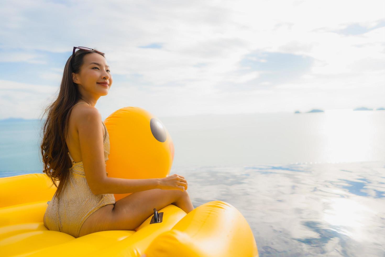 portret jonge aziatische vrouw op opblaasbare vlotter gele eend rond buitenzwembad in hotel en resort foto