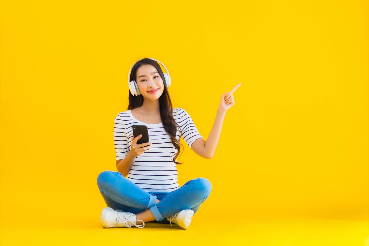 portret mooie jonge aziatische vrouw gebruik slimme mobiele telefoon met hoofdtelefoon foto