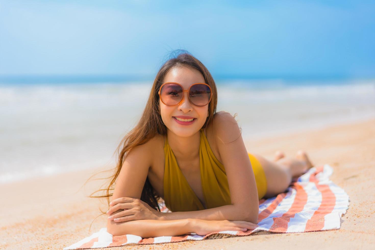 portret mooie jonge aziatische vrouw glimlach gelukkig op het strand en de zee foto