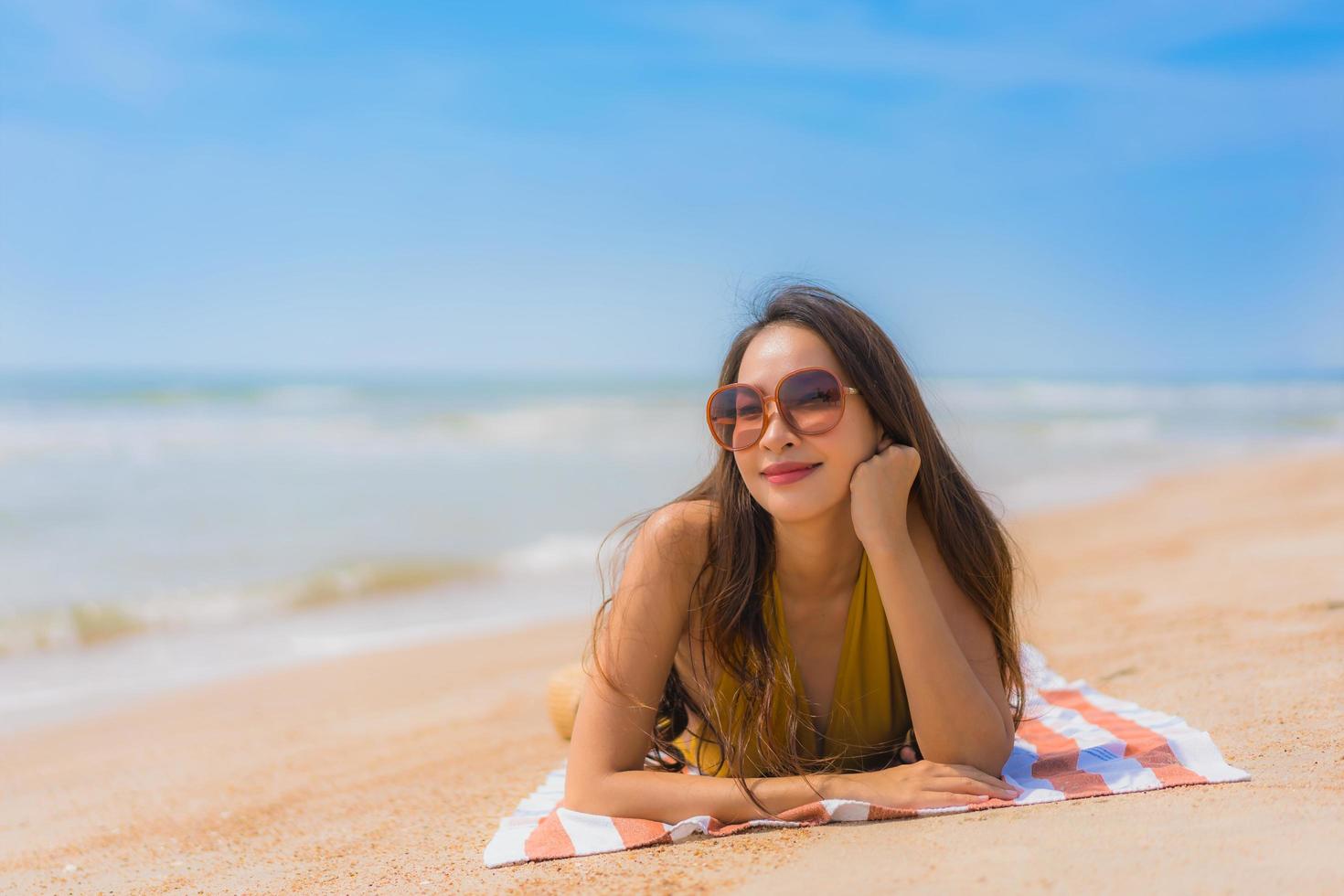 portret mooie jonge aziatische vrouw glimlach gelukkig op het strand en de zee foto