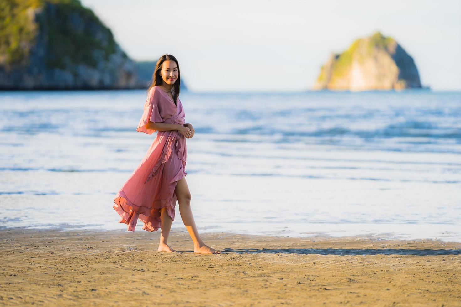 portret jonge mooie Aziatische vrouw lopen glimlach en gelukkig op het strand zee en oceaan and foto