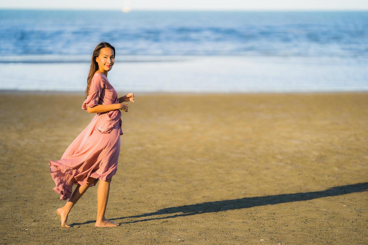 portret jonge mooie Aziatische vrouw lopen glimlach en gelukkig op het strand zee en oceaan and foto