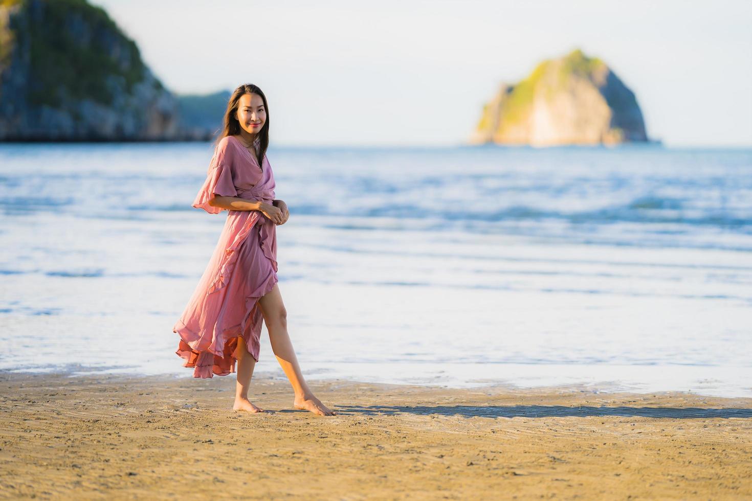 portret jonge mooie Aziatische vrouw lopen glimlach en gelukkig op het strand zee en oceaan and foto