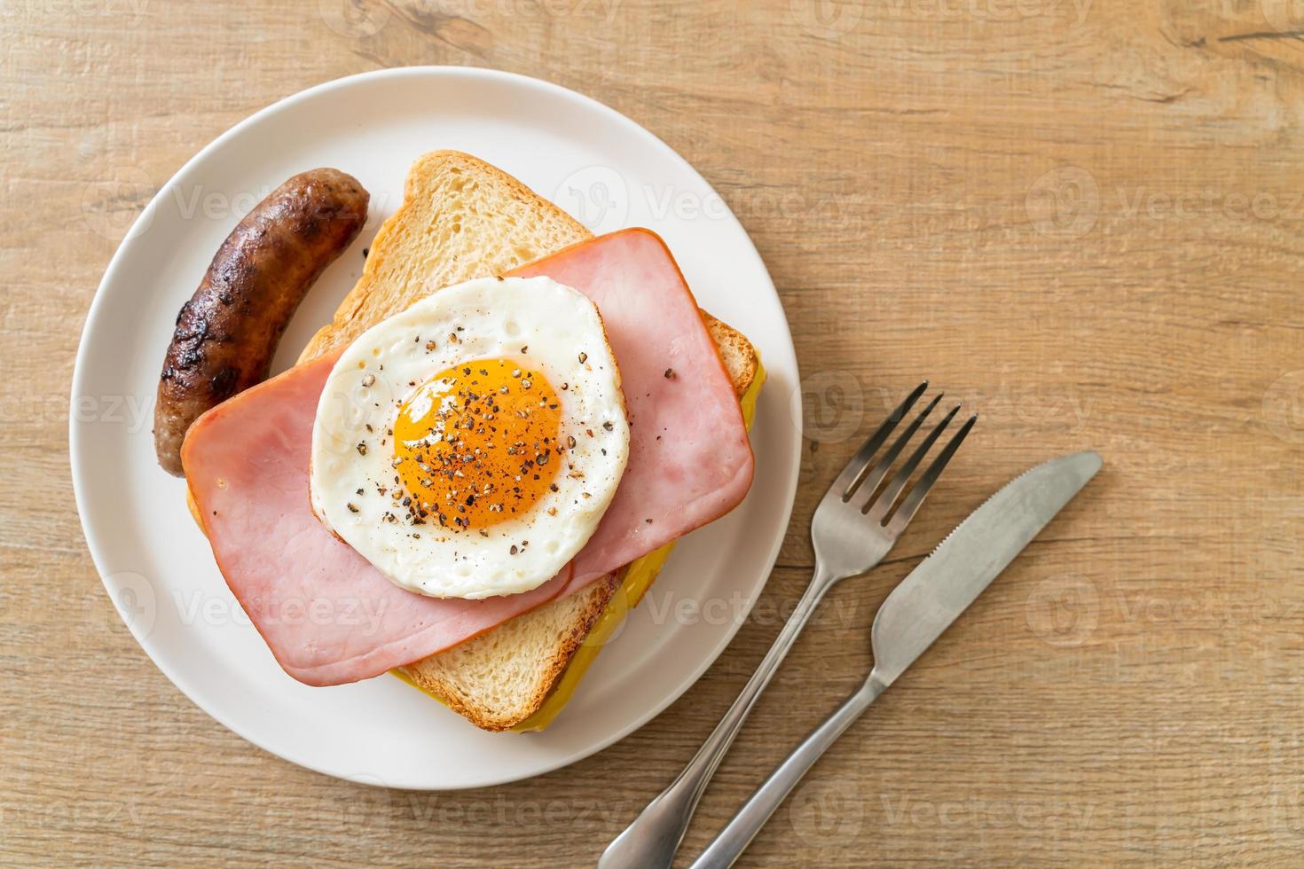 zelfgebakken brood geroosterde kaas belegde ham en gebakken ei met varkensworst als ontbijt foto