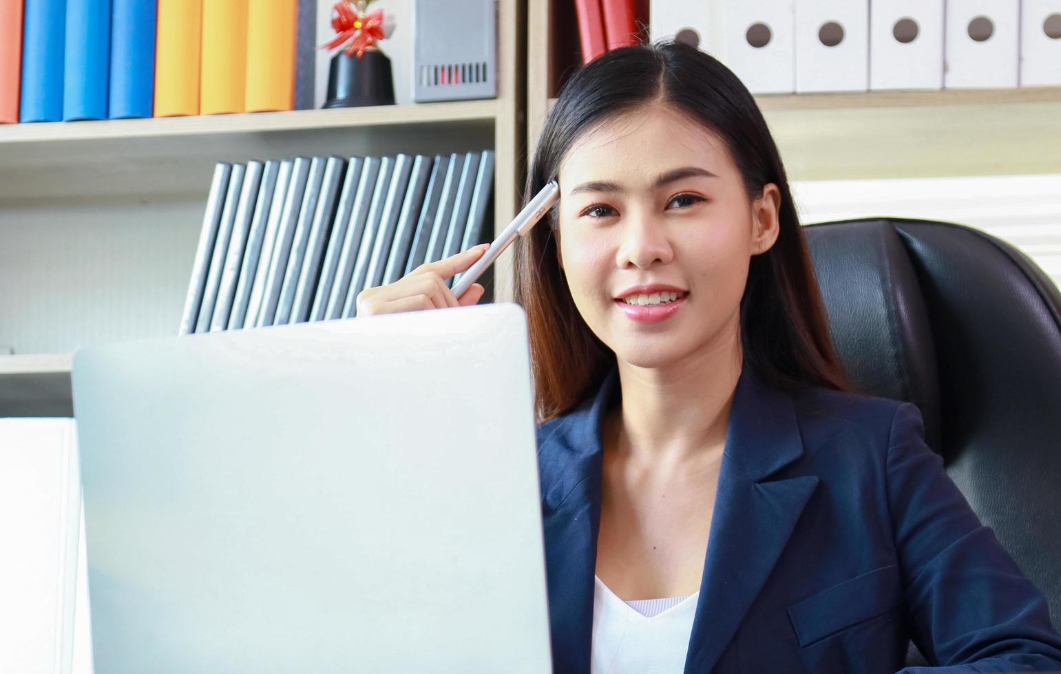 vrouw in een geel pak zit op kantoor en denkt aan marketing foto