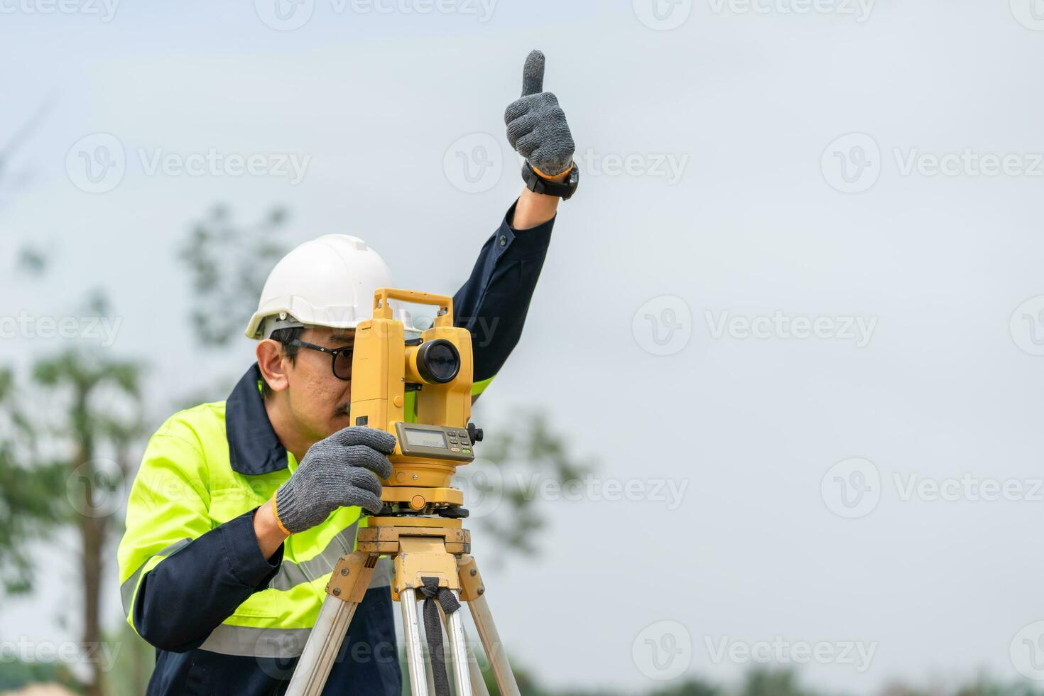 landmeter civiel ingenieur duimen omhoog met uitrusting Aan de bouw plaats. foto