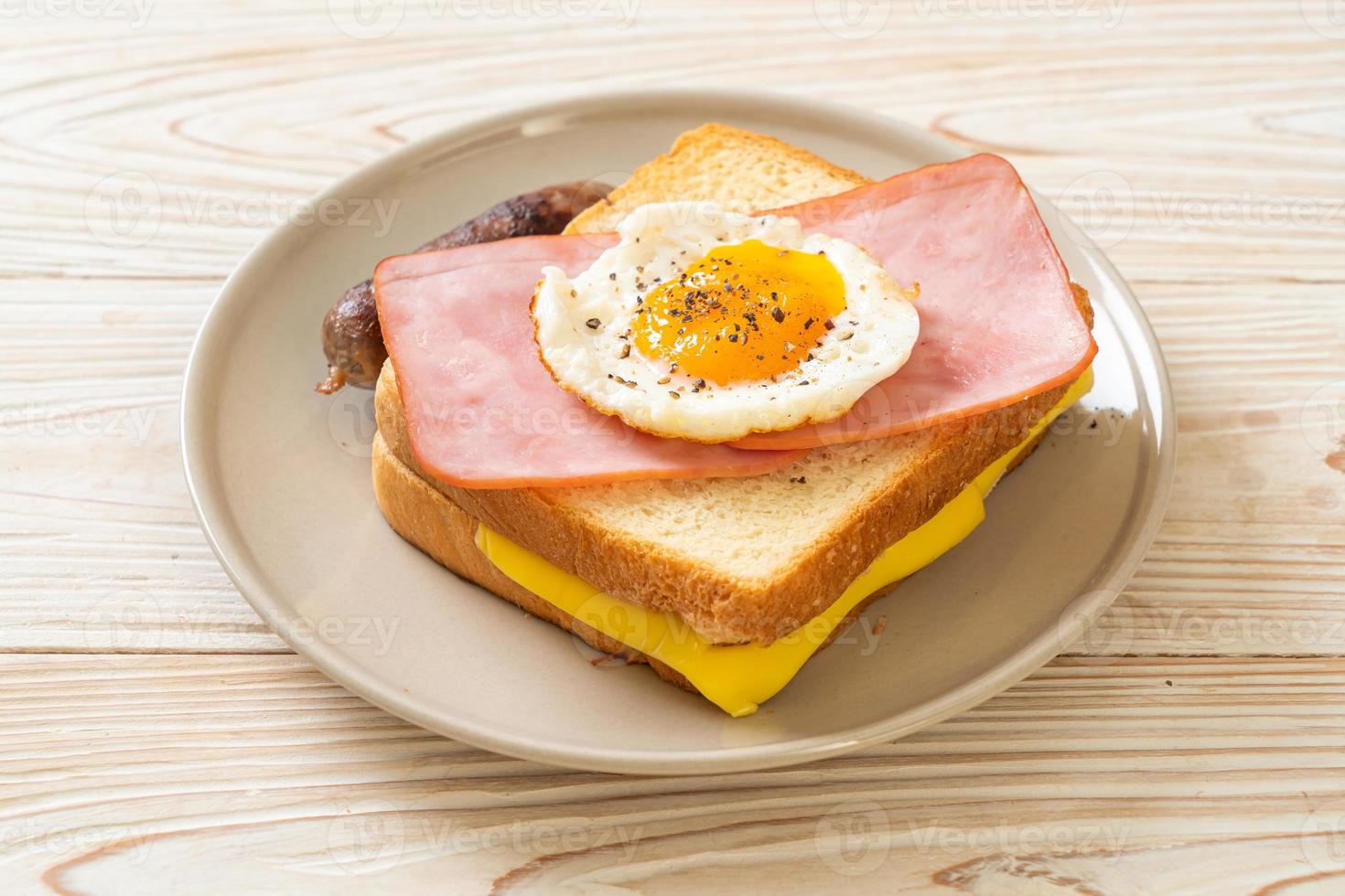 zelfgebakken brood geroosterde kaas, belegde ham en gebakken ei met varkensworst als ontbijt foto