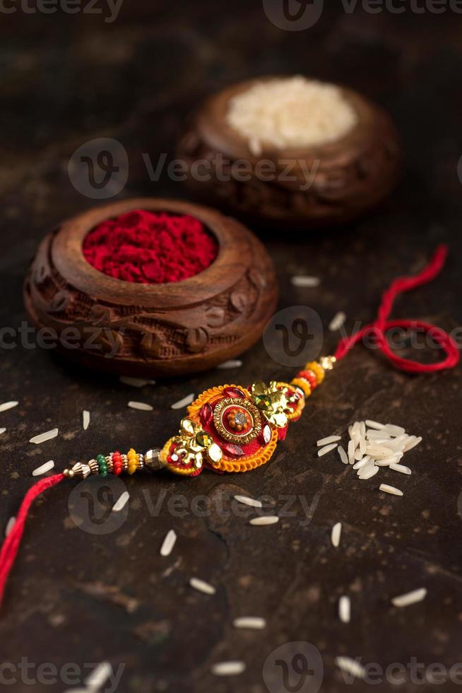 raksha bandhan achtergrond met een elegante rakhi, rijstkorrels en kumkum. een traditionele Indiase polsband die een symbool is van liefde tussen broers en zussen. foto