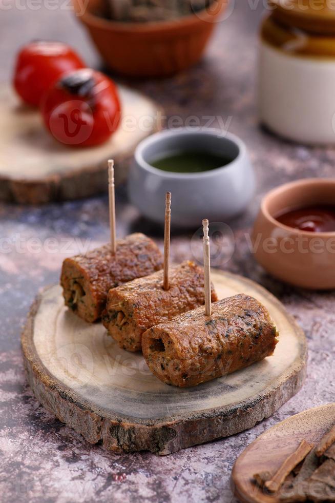 Indiaas eten kip seekh kebab op een houten schotel met saus foto